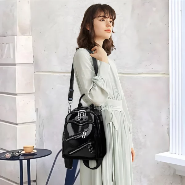 Femme portant un Sac à Dos en Cuir Verni Noir Zips Lames de Rasoir en bandoulière Femme portant un Sac à Dos en Cuir Verni Noir Zips Lames de Rasoir en bandoulière.