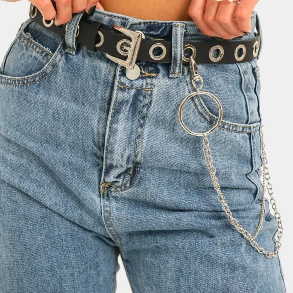 Femme portant une Ceinture Œillets Cuir Noir avec Double Chaîne Pendante Femme portant une Ceinture Œillets Cuir Noir avec Double Chaîne Pendante.