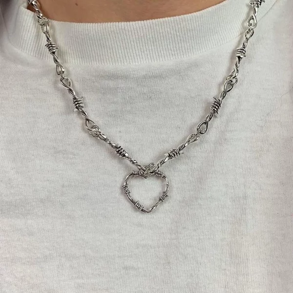 Homme Gothique portant un Collier en Fil Barbelé Chaîne et Pendentif Cœur Homme Gothique portant un Collier en Fil Barbelé Chaîne et Pendentif Cœur.