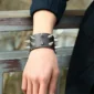Homme avec un Bracelet Similicuir Noir à Deux Rangées de Pointes Métal.