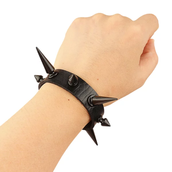 Homme portant un Bracelet Punk Clouté en Similicuir Noir avec Spikes Noirs Asymétriques Homme portant un Bracelet Punk Clouté en Similicuir Noir avec Spikes Noirs Asymétriques.