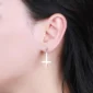 Femme avec Boucles d’Oreilles Croix Inversée Acier 316L.