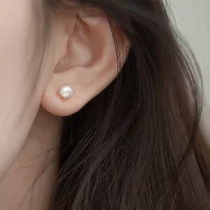 Femme avec Boucles d'Oreilles Perle Sertie à Griffes Acier 316L.