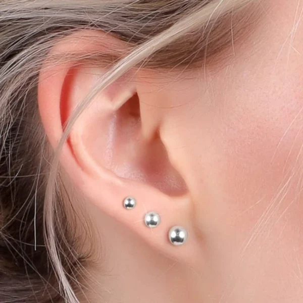 Femme avec Clous d’oreilles Acier 316L à Boules Femme avec Clous d’oreilles Acier 316L à Boules.