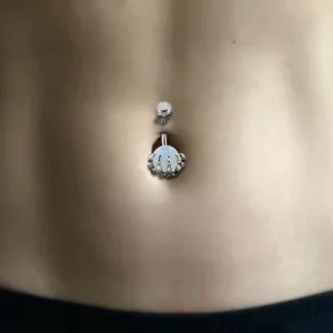 Femme avec Piercing Nombril Sphère Sertie d’une Main Squelettique.