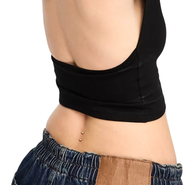Femme avec Piercing de Surface Agrafe en Titane à Pointes au Bas du Dos Femme avec Piercing de Surface Agrafe en Titane à Pointes au Bas du Dos.