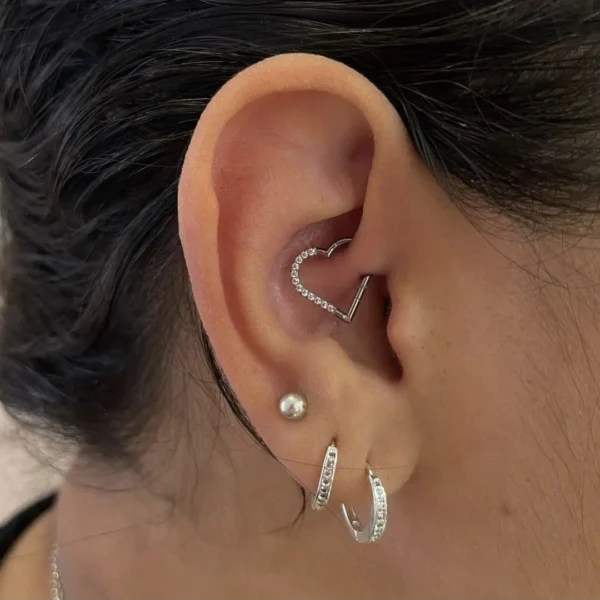 Femme avec un Piercing Cœur Asymétrique en Titane à Zircons Sertis au Daith Femme avec un Piercing Cœur Asymétrique en Titane à Zircons Sertis au Daith.
