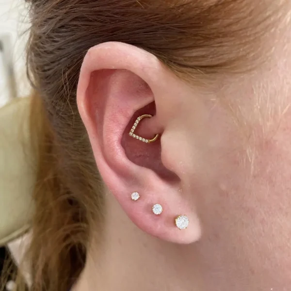 Femme portant un Piercing Clicker Titane - Élégance Angulaire & Zircons au Daith Femme portant un Piercing Clicker Titane - Élégance Angulaire & Zircons au Daith.