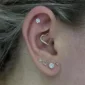 Femme portant un Piercing Cœur Asymétrique en Titane Anodisé Doré à Zircons Sertis au Daith.