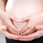 Femme portant un Piercing Nombril de Grossesse à Pendentif Pieds de Bébé.