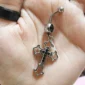 Femme tenant un Piercing Nombril Croix Gothique Ornementale Ajourée & Zircons Noirs.