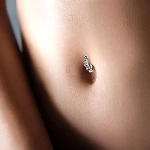 Femme portant un Piercing Anneau Nombril Clicker Têtes de Mort en Argent 925 Femme portant un Piercing Anneau Nombril Clicker Têtes de Mort en Argent 925.