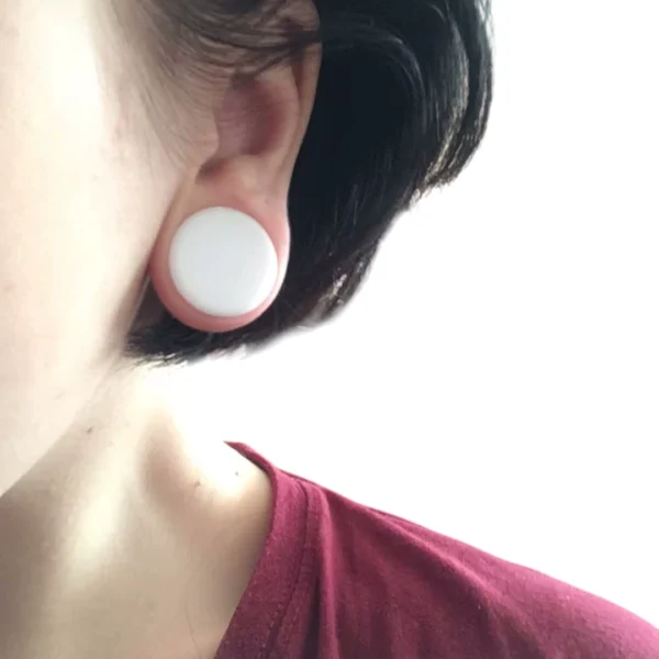 Femme portant un Écarteur Plug Double Évasé en Acrylique Blanc Femme portant un Écarteur Plug Double Évasé en Acrylique Blanc.