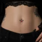 Femme Gothique avec Piercing Nombril Cœur Ailé et Chaînes Pendantes.