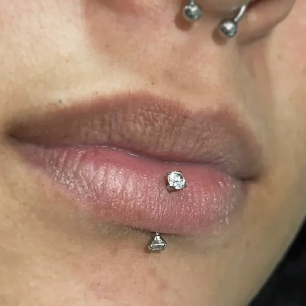 Femme avec Piercing Banane Titane Double Zirconium Griffé en Labret Vertical (lèvre) Femme avec Piercing Banane Titane Double Zirconium Griffé en Labret Vertical (lèvre).