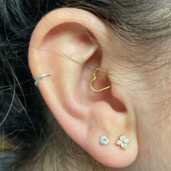 Femme avec un Piercing Cœur en Titane Anodisé Doré à l'Oreille (Daith) Femme avec un Piercing Cœur en Titane Anodisé Doré à l'Oreille (Daith).