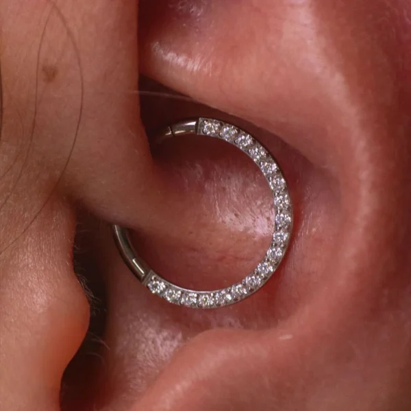 Piercing Anneau Charnière Titane à Arc Pavé de Zirconiums au Daith Piercing Anneau Charnière Titane à Arc Pavé de Zirconiums au Daith.