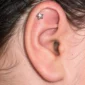 Femme avec Piercing Étoile Labret 16G Titane à l'Hélix.