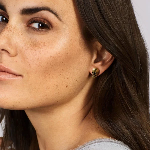 Femme portant des Boucles d’Oreilles Crâne Acier Inoxydable Poli Effet Vieilli Finition Dorée Femme portant des Boucles d’Oreilles Crâne Acier Inoxydable Poli Effet Vieilli Finition Dorée.