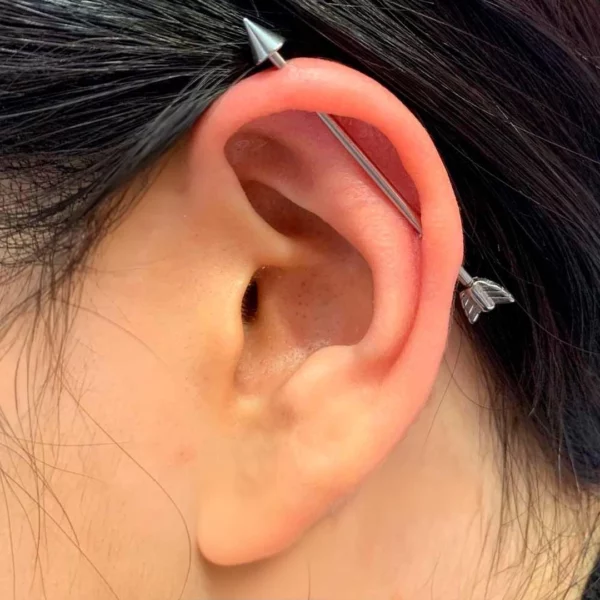 Femme avec un Piercing Flèche Type Industriel en Acier Chirurgical 1.2×38 mm Femme avec un Piercing Flèche Type Industriel en Acier Chirurgical 1.2×38 mm.