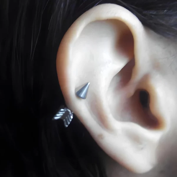Femme avec un Piercing Flèche en Acier 1.2×6 mm à l'Hélix Femme avec un Piercing Flèche en Acier 1.2×6 mm à l'Hélix.