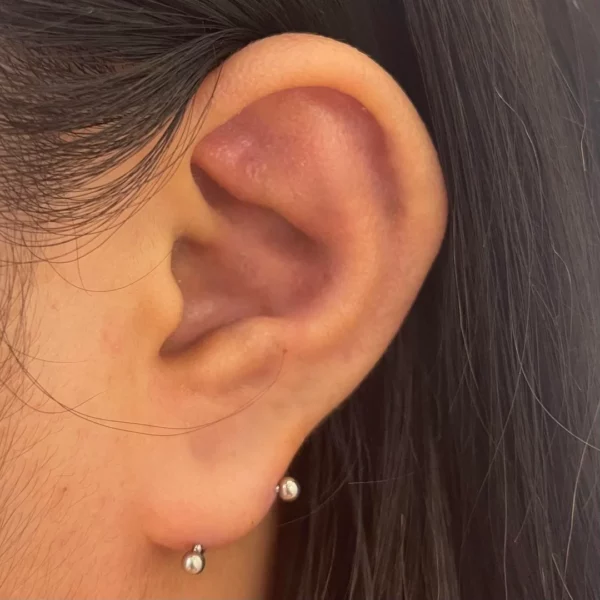 Femme portant un Piercing Banane 18 mm au Lobe Transversal Femme portant un Piercing Banane 18 mm au Lobe Transversal.