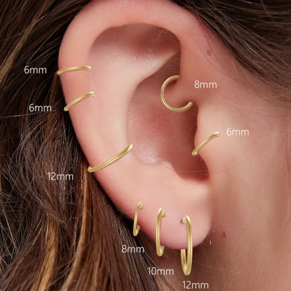 Femme avec des Piercings Clicker Anneaux en Titane à l'Oreille Femme avec des Piercings Clicker Anneaux en Titane à l'Oreille.
