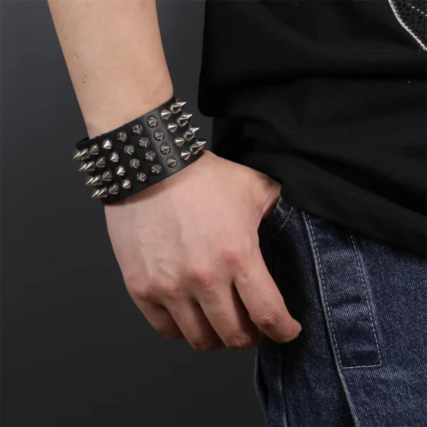 Homme avec un Bracelet clouté en cuir véritable à 4 rangées de clous Homme avec un Bracelet clouté en cuir véritable à 4 rangées de clous.