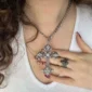 Femme portant un Collier à Pendentif Croix Gothique Stylisée Constellée de Zircons.
