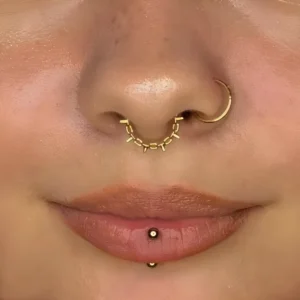 Femme avec un Piercing Anneau Clicker Chaîne Maillons à Pointes Fines au Septum.