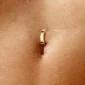 Femme avec un Piercing Nombril Anneau Clicker en Titane Anodisé Doré.