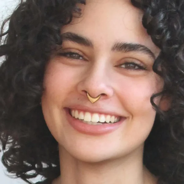 Femme portant un Piercing Anneau Clicker à Triangle Plein en Acier 316L Doré PVD au Septum Femme portant un Piercing Anneau Clicker à Triangle Plein en Acier 316L Doré PVD au Septum.
