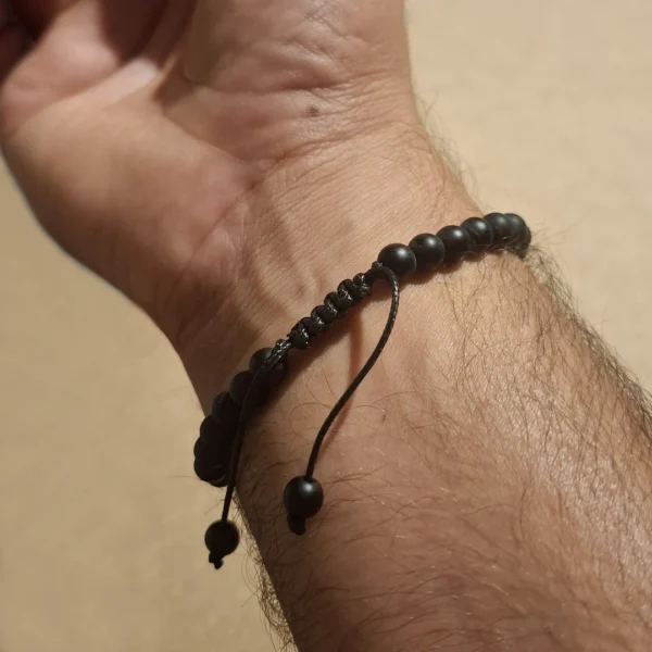 Homme avec un Bracelet Onyx Mat & Œil de Tigre 6mm à Cordon Réglable Homme avec un Bracelet Onyx Mat & Œil de Tigre 6mm à Cordon Réglable.