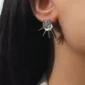 Femme Punk avec des Boucles d'Oreilles à Pointes Noires & Zircon à Facettes