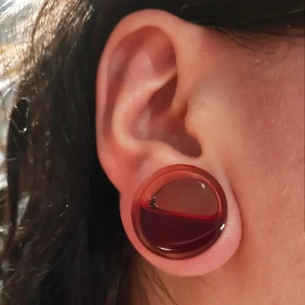 Femme avec un Écarteur Plug en Acrylique avec Liquide Rouge Sang de 25 mm au Lobe Femme avec un Écarteur Plug en Acrylique avec Liquide Rouge Sang de 25 mm au Lobe.