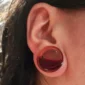 Femme avec un Écarteur Plug en Acrylique avec Liquide Rouge Sang de 25 mm au Lobe.