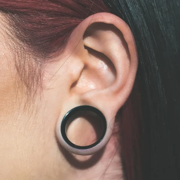 Femme avec un Écarteur Tunnel Acier 316L Double Évasé & Dévissable au Lobe (oreille) Femme avec un Écarteur Tunnel Acier 316L Double Évasé & Dévissable au Lobe (oreille).