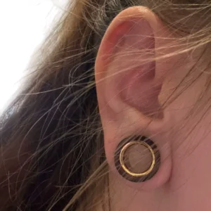 Femme avec un Écarteur Tunnel en Bois de Santal & Acier Doré au Lobe.