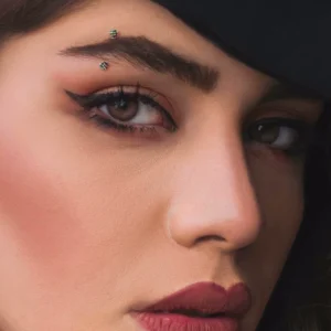 Femme portant un Piercing Banane 12 mm avec Boules à Striures à l'Arcade Sourcilière.