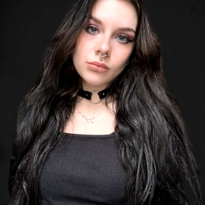 Femme total look noir avec piercings au septum, narine, labret et lèvre.