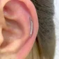 Femme avec Piercing Oreille (cartilage) de type Labret à Motif Double Ligne Courbée.
