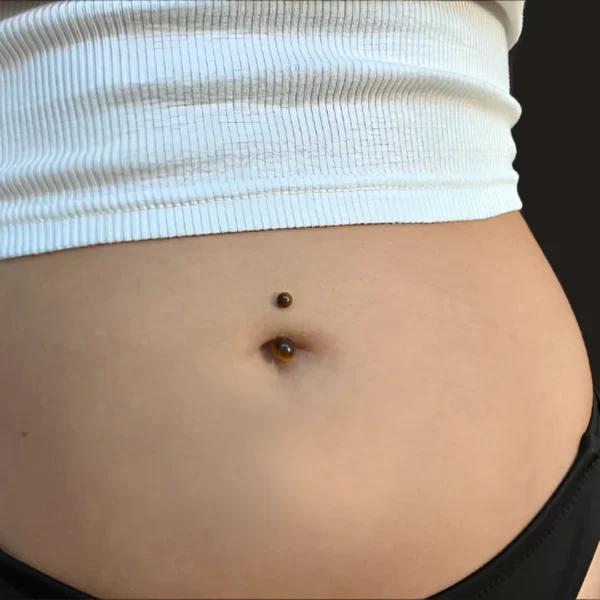 Femme avec Piercing à Perles d'Oeil de Tigre au Nombril Femme avec Piercing à Perles d'Oeil de Tigre au Nombril.