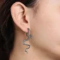Femme avec Boucles d’Oreilles Serpent Traversant en Acier 316L.