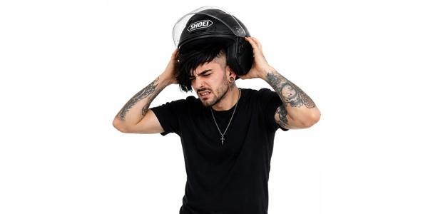 Homme peinant à ajuster son casque de moto à cause de ses piercings oreille.